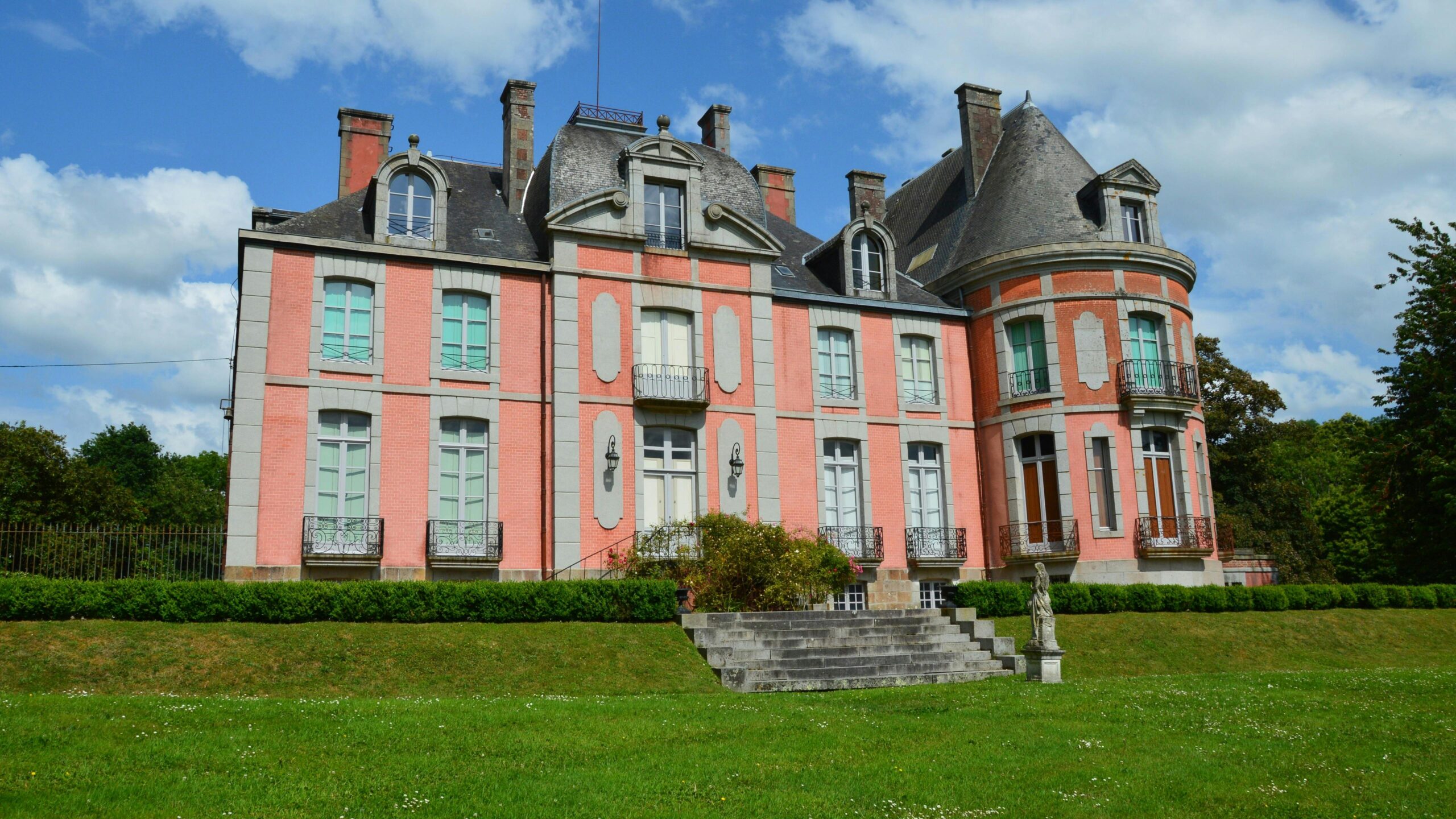 A picturesque chateau in Bacilly, Normandie, France under a bright summer sky.
